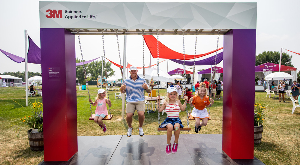 Family swinging on swings within a 3M branded arch