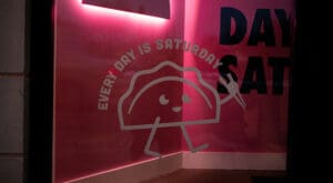 Backlit window signage with "every day is a Saturday" message.