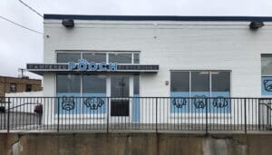 Outdoor image of the facade of the Pampered Pooch Playground building. Windows are covered in light blue vinyl decals depicting dogs.