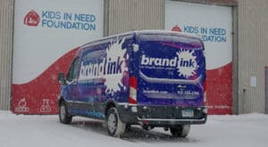 The Brand ink van is parked in front of two colorful loading docks at the Kids in Need Foundation headquarters.