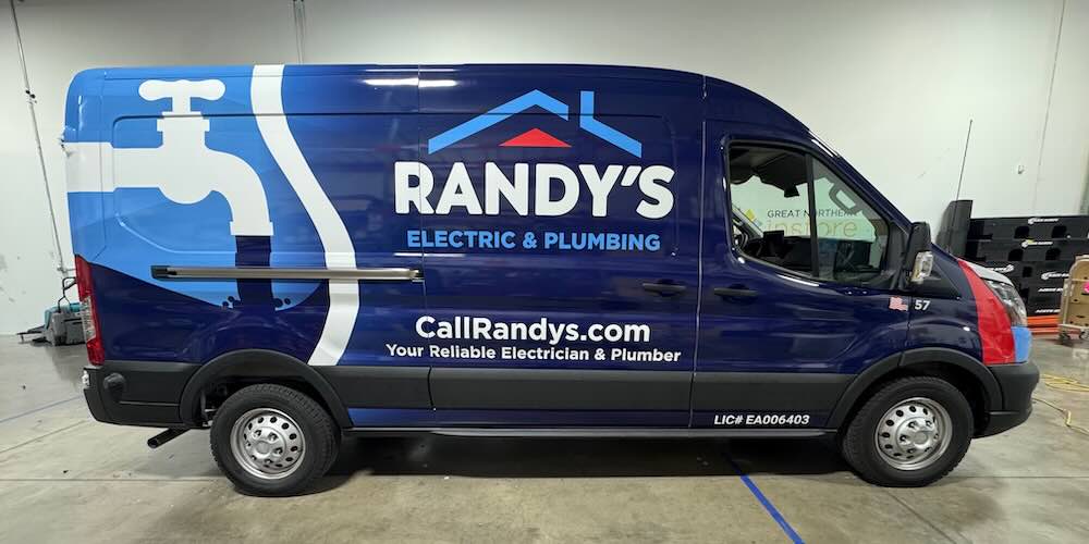 A newly wrapped Ford Transit advertising Randy's Electric & Plumbing waits in the installation bay at Brand ink
